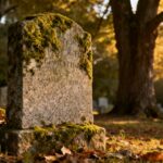 Weathered granite headstone in a peaceful cemetery setting.